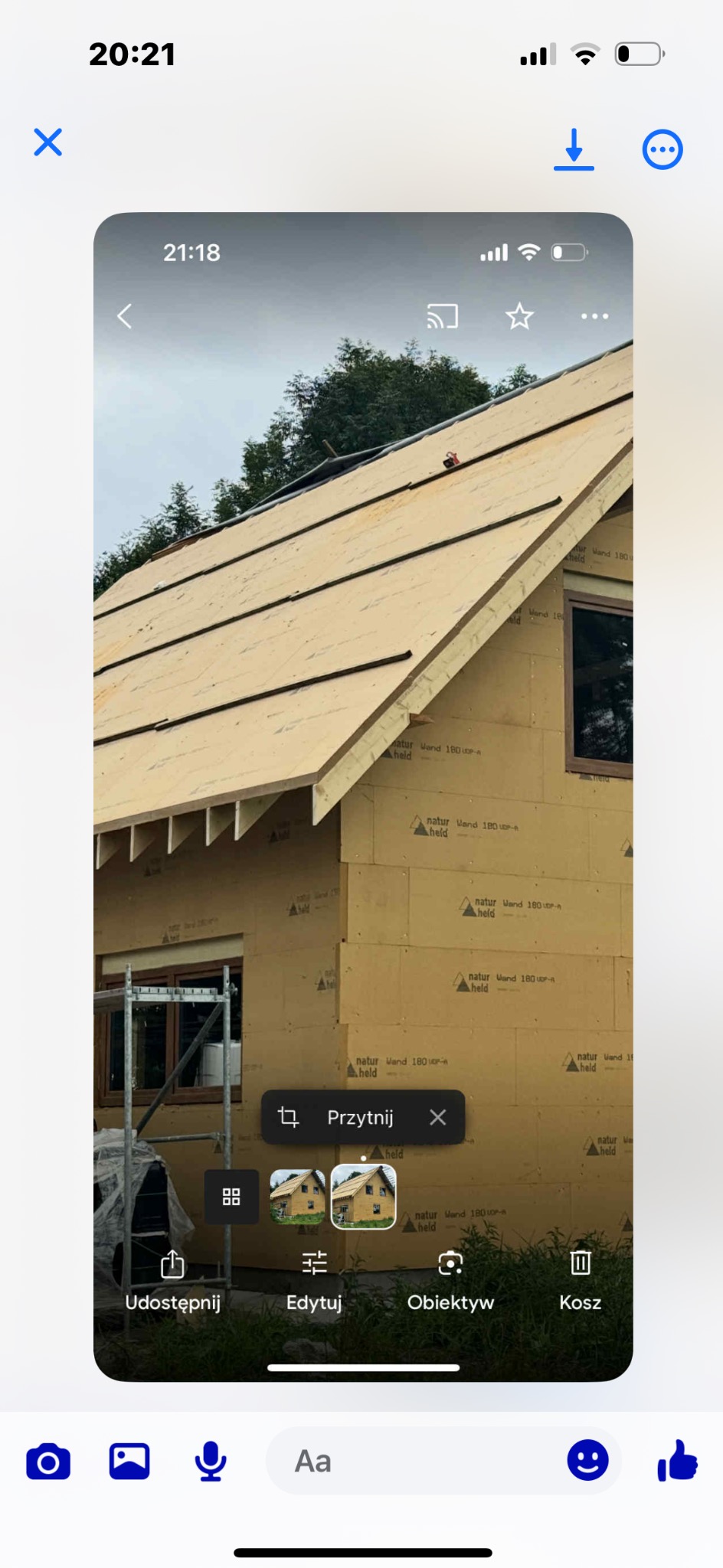 Budowa domu jednorodzinnego: ściany z płyt izolacyjnych i przygotowany dach z łatami. Widoczne rusztowania i okna. Etap prac przed ociepleniem poddasza.