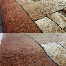 Fragment dywanu z geometrycznym wzorem, widoczna różnica w czystości między górną a dolną częścią, włosie w odcieniach brązu i beżu.