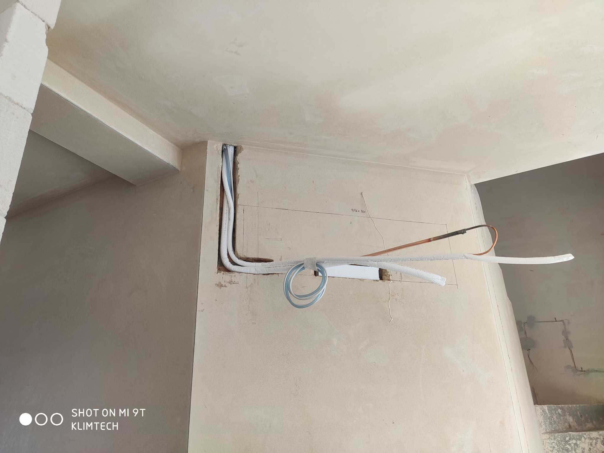 Wewnętrzna instalacja przewodów chłodniczych i elektrycznych w ścianie podczas montażu systemu klimatyzacji w surowym wnętrzu.