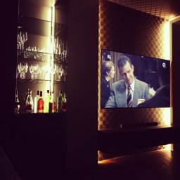 Lignum Design S.C. Monika Jakubowska Zbigniew Krupa - Nowoczesny salon z podświetlaną szafką na alkohole i kieliszki oraz telewizorem na ścianie z dekoracyjną tapetą.