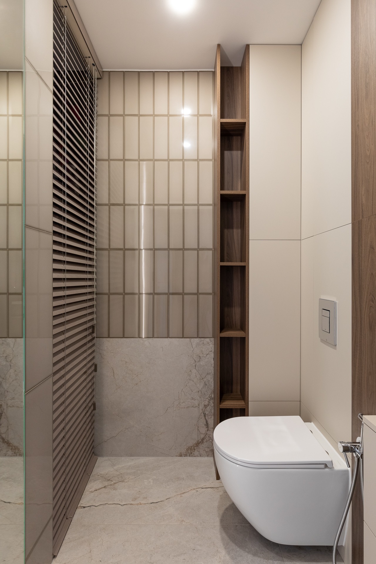 Nowoczesna łazienka z podwieszaną toaletą, beżowymi płytkami imitującymi cegłę, drewnianymi półkami i marmurową podłogą.