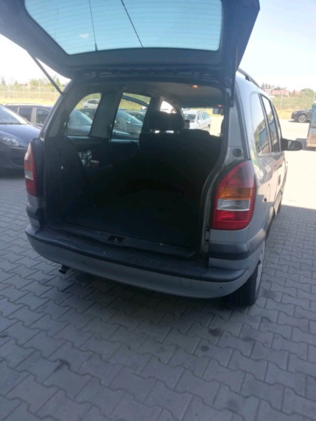 Otwarty bagażnik szarego kombi na parkingu, widok z tyłu, pusta przestrzeń ładunkowa.