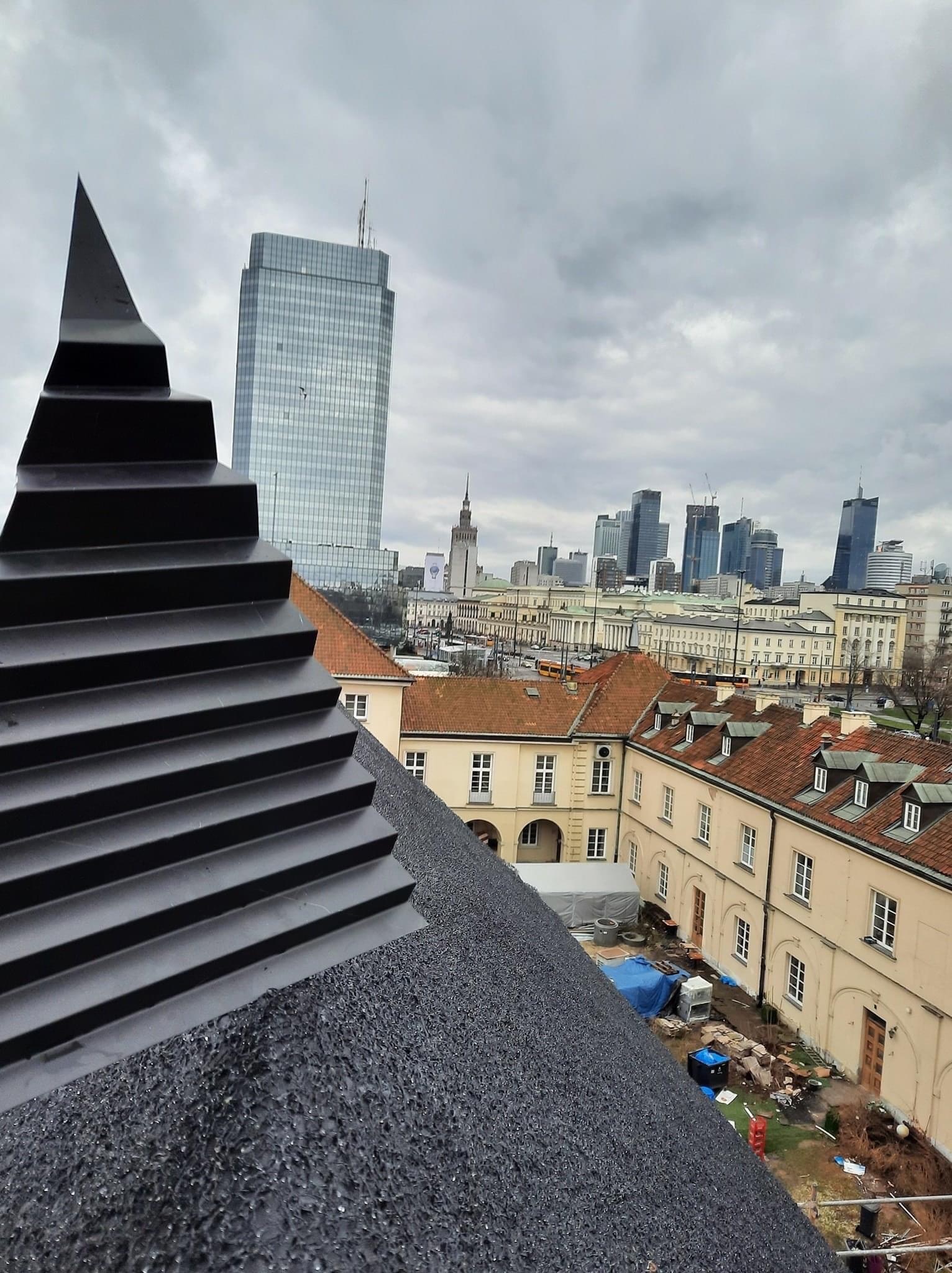 Nowe pokrycie dachowe z czarnego gontu bitumicznego na dachu budynku w centrum Warszawy, widok na panoramę miasta i Pałac Kultury