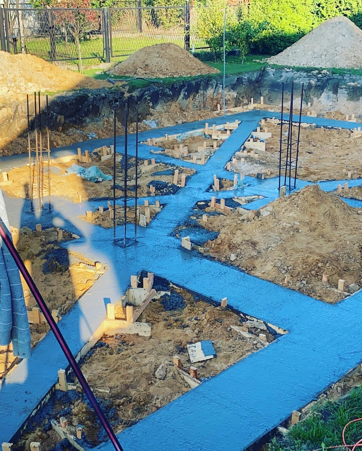 Fundamenty w trakcie zalewania betonem, widoczne drewniane szalunki i zbrojenia, teren budowy w Rybniku.