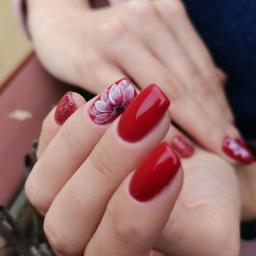 Adrianna Zajączek - Czerwony manicure hybrydowy z brokatowym akcentem i ręcznie malowanym białym kwiatem na jednym paznokciu.