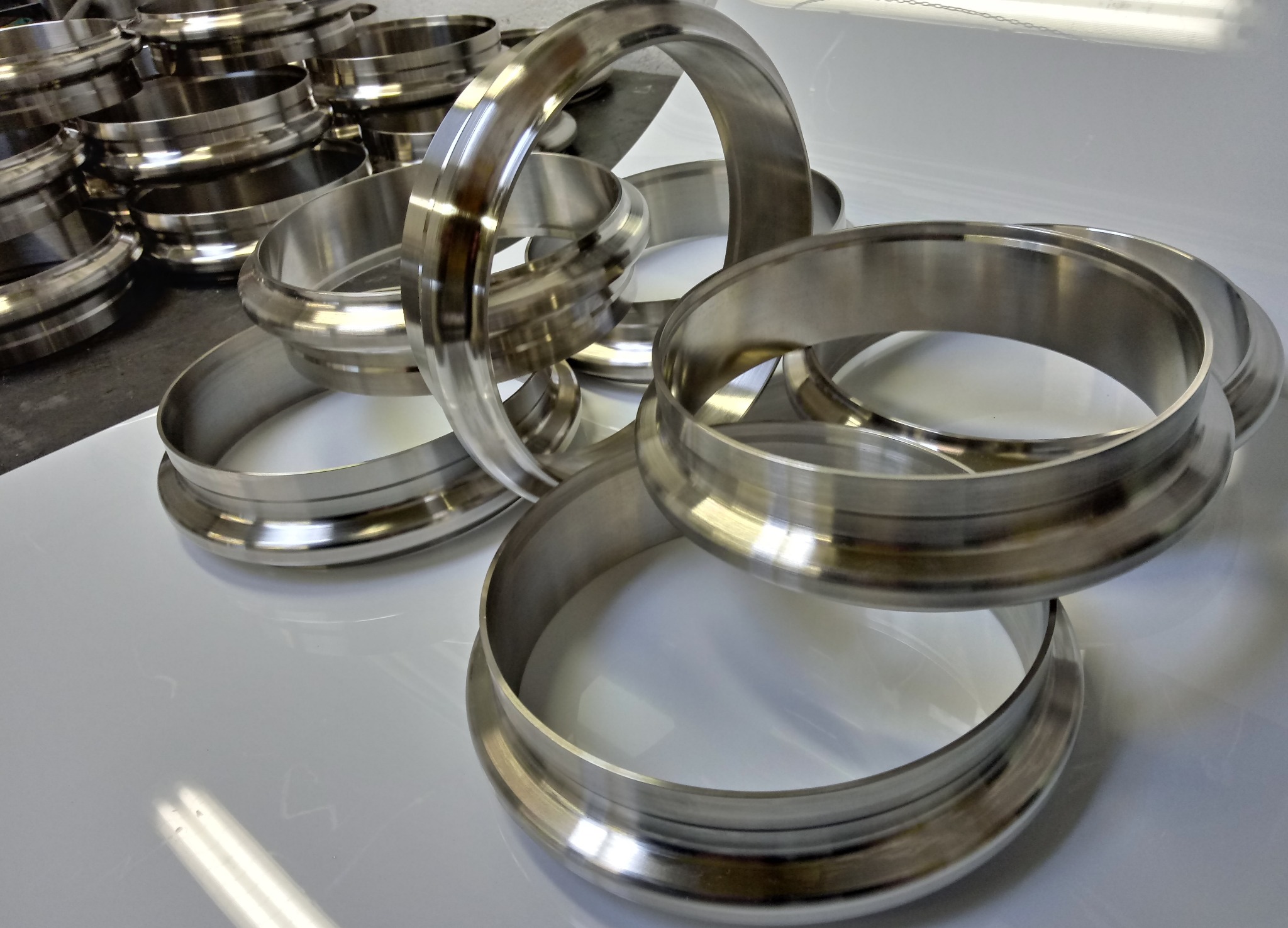 Stalowe, precyzyjnie wykonane pierścienie z obrobionymi krawędziami, ułożone na błyszczącej, białej powierzchni.