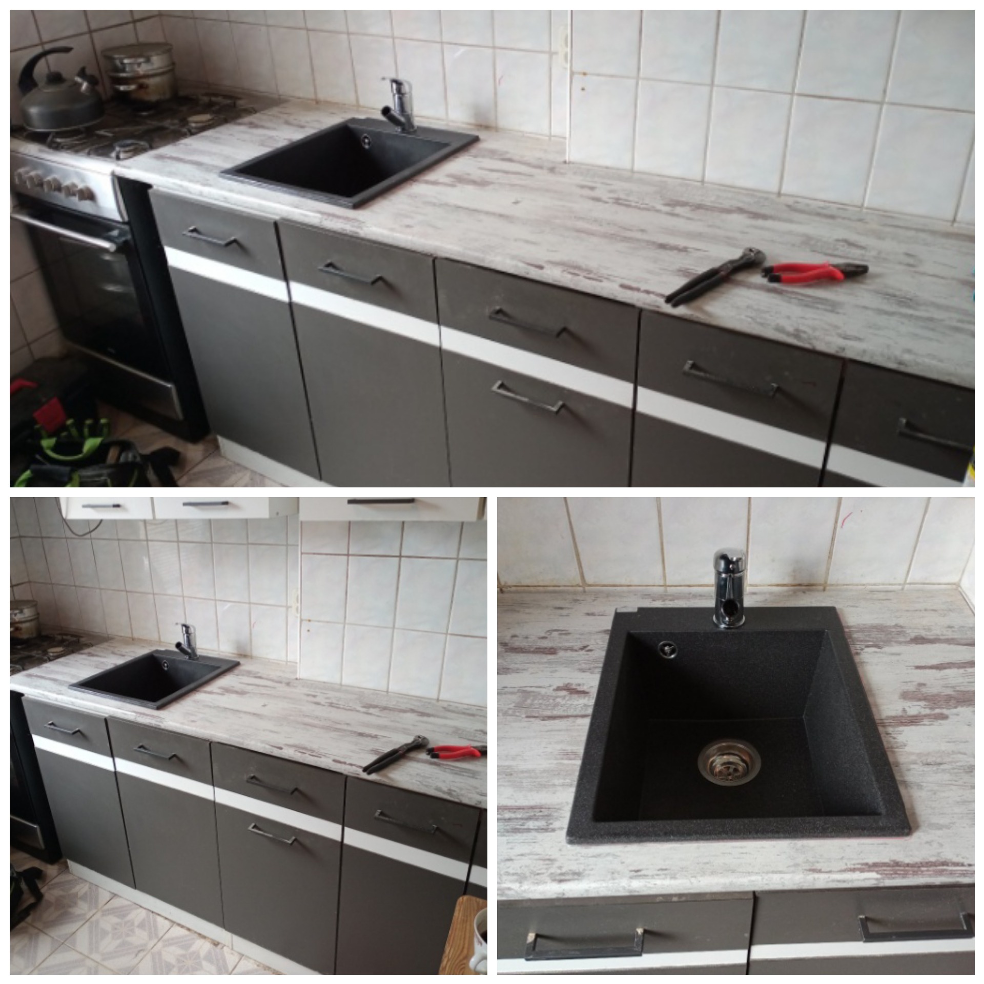 Czarny zlewozmywak granitowy z chromowaną baterią zamontowany w blacie o fakturze postarzanego drewna, na tle białych płytek i szarych szafek kuchennych z białymi paskami; na blacie leżą szczypce...