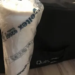 Rolka białego materiału Veltex Medilux 62607 w plastikowym opakowaniu, częściowo zasłonięta przez czarny pokrowiec Quirl-mo Health.