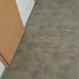 Świeżo ułożone, szare panele podłogowe w pustym pokoju z dwiema drewnianymi ościeżnicami drzwiowymi.