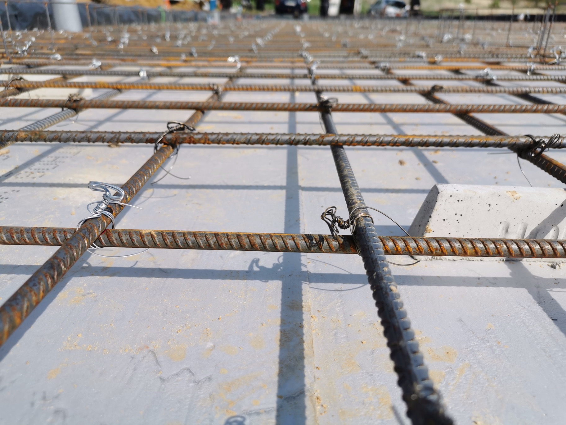 Zbrojenie płyty fundamentowej z betonu, siatka z prętów stalowych połączonych drutem wiązałkowym, widok z bliska na konstrukcję przed zalaniem betonem.