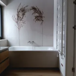 Nowoczesna łazienka z wanną obudowaną płytami, ozdobną tapetą z motywem roślinnym, drewnopodobną podłogą i grzejnikiem drabinkowym w kolorze białym.