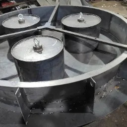 Metalowa konstrukcja w kształcie pierścienia z trzema cylindrycznymi zbiornikami wewnątrz, połączona stalowymi belkami, widoczne spawy i elementy mocujące.