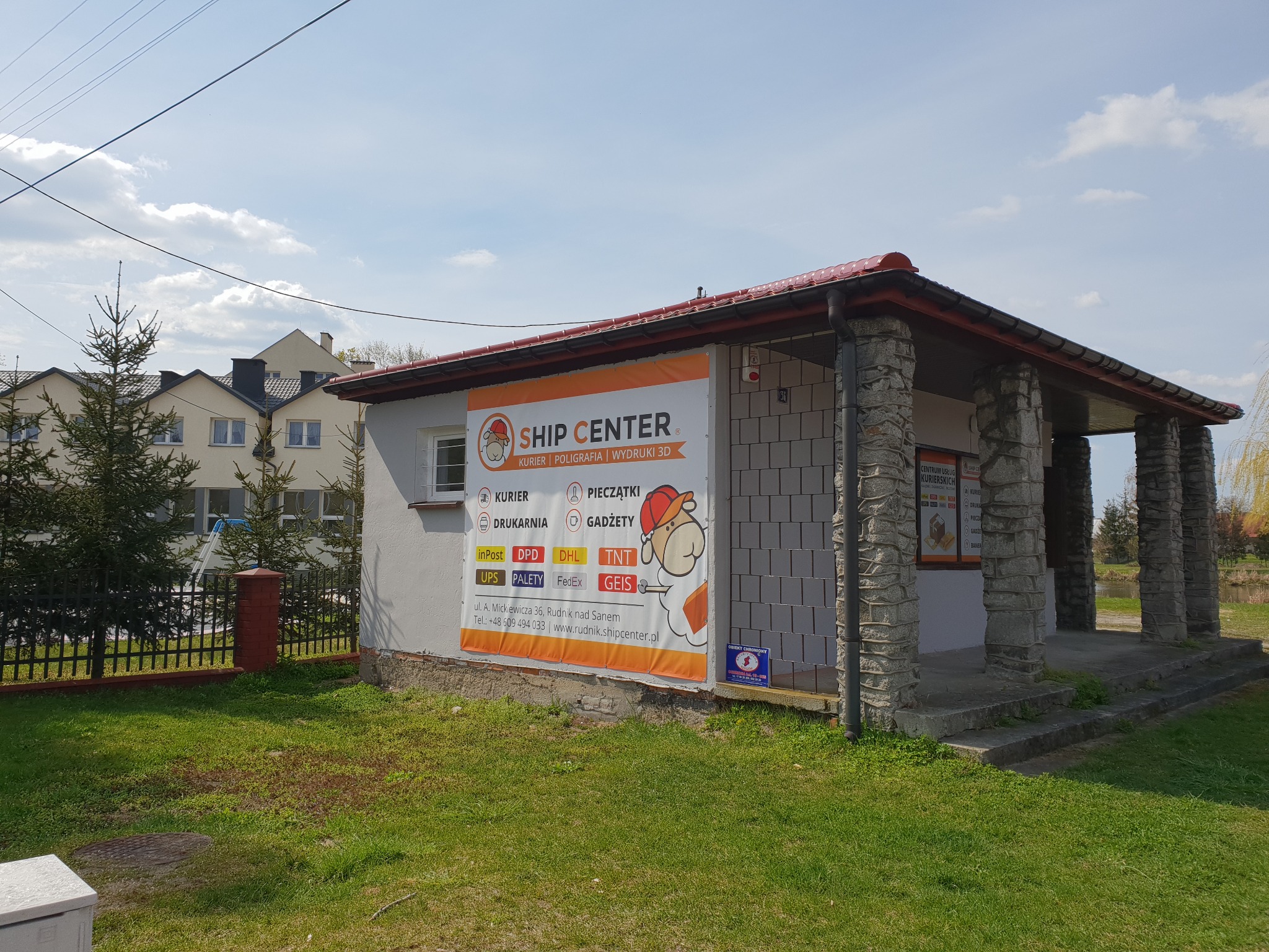 Budynek Ship Center w Rudniku nad Sanem z dużym banerem reklamowym informującym o usługach kurierskich, poligraficznych i druku 3D.