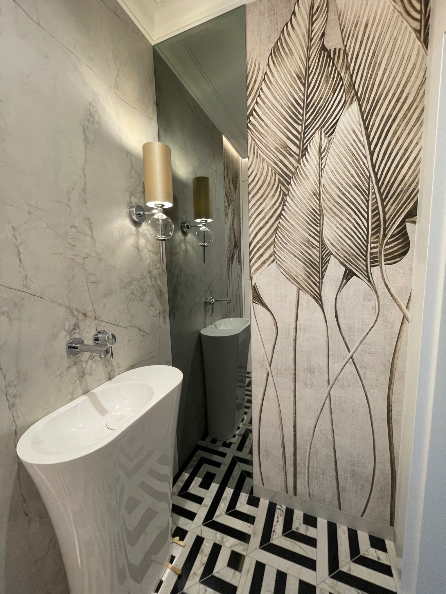 Nowoczesna łazienka z wolnostojącą umywalką, marmurową ścianą, tapetą w liście i geometryczną podłogą w czarno-białe wzory.