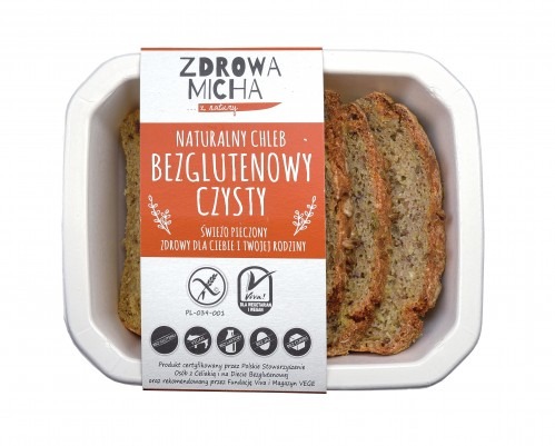 Kromki chleba bezglutenowego z ziarnami, zapakowane w białe pudełko z etykietą 'Zdrowa Micha', prezentujące certyfikaty i informacje o produkcie.