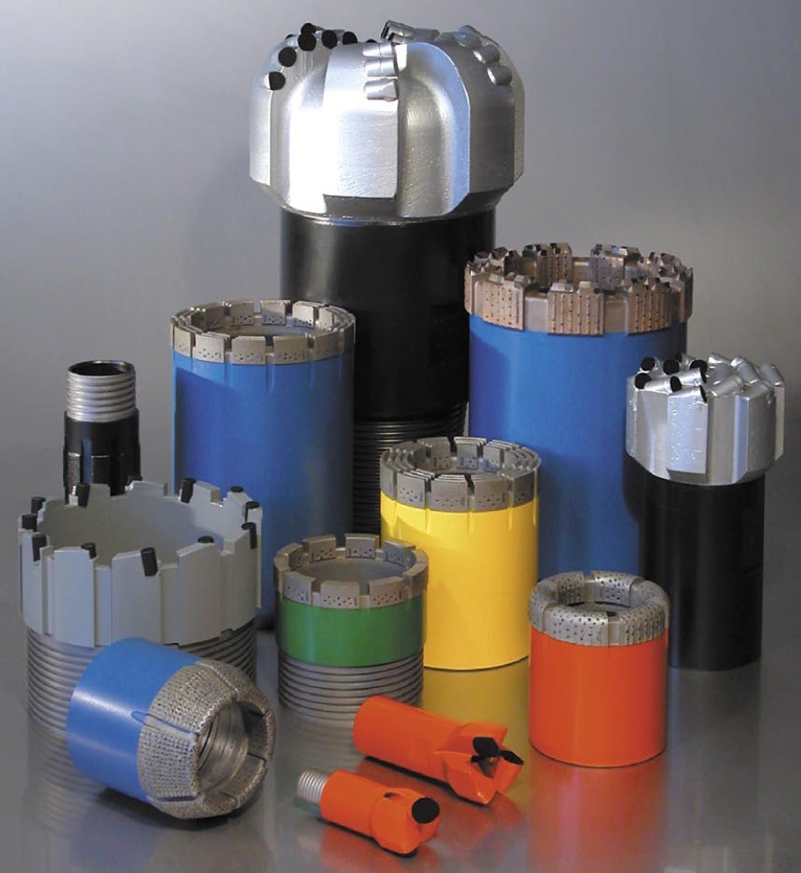 Zestaw różnokolorowych wierteł koronowych i świdrów diamentowych do zastosowań w geologii, górnictwie oraz przemyśle naftowym i gazowym, ułożonych na gładkiej powierzchni.