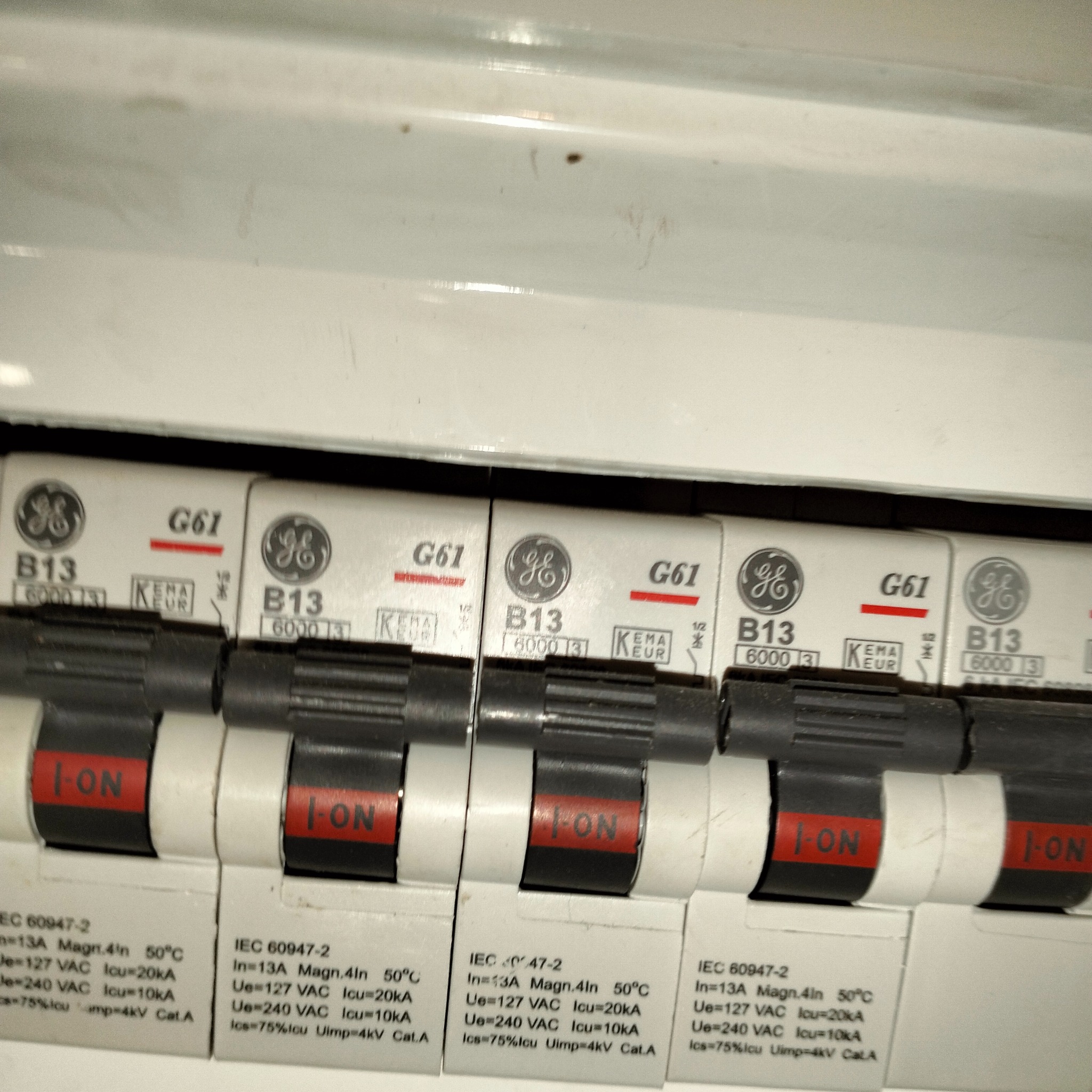 Szczegółowe ujęcie tablicy rozdzielczej z wyłącznikami nadprądowymi B13 firmy GE, widoczne oznaczenia i parametry techniczne.