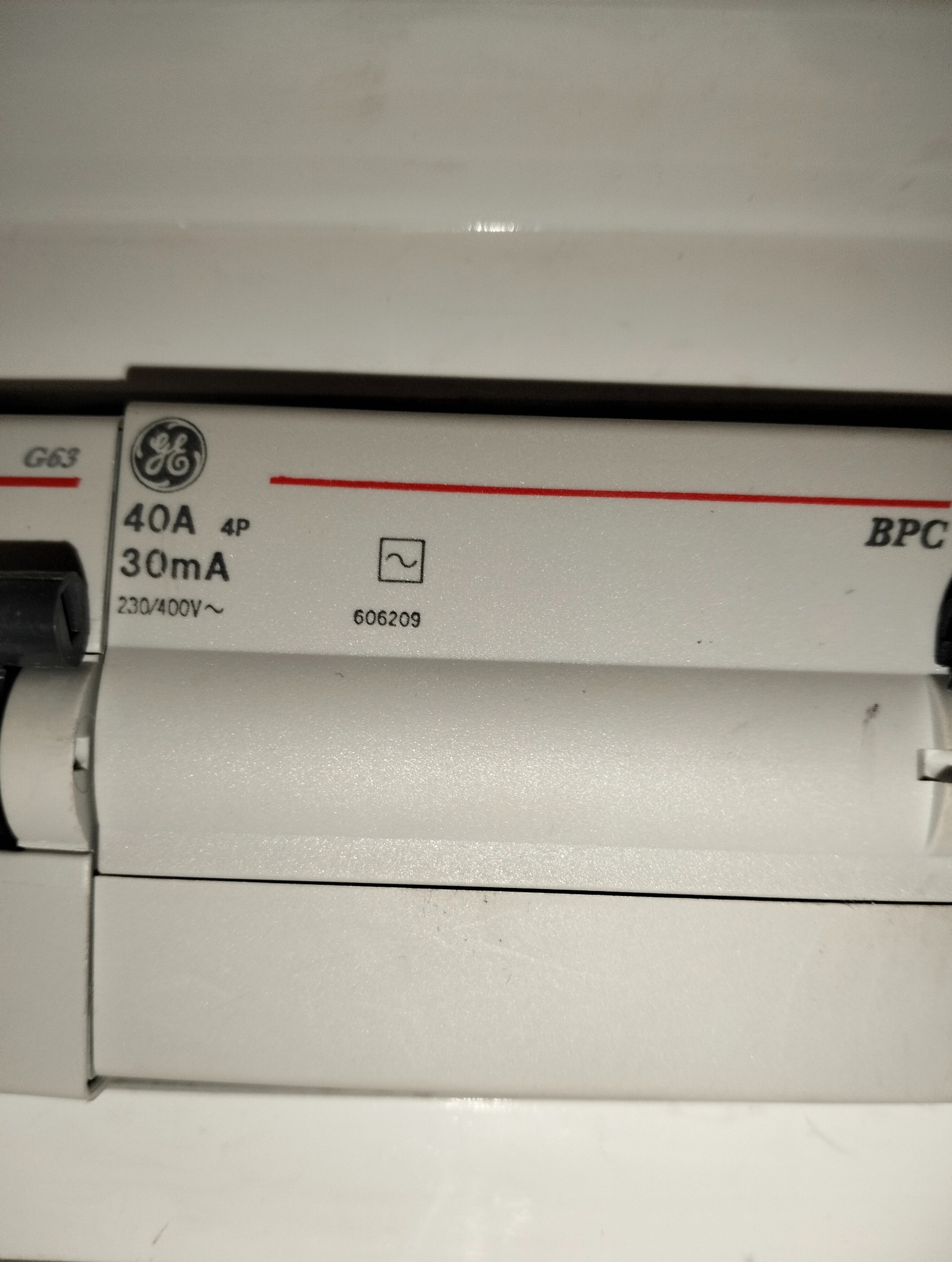 Szczegółowy widok wyłącznika różnicowoprądowego GE 40A 4P 30mA 230/400V~ z numerem seryjnym 606209, zamontowanego w białej obudowie.