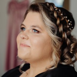 Studio Urody Endorfina - Portret kobiety z upiętymi włosami w warkocze, ozdobionymi perłami. Delikatny makijaż podkreśla niebieskie oczy. W tle widoczna suknia.