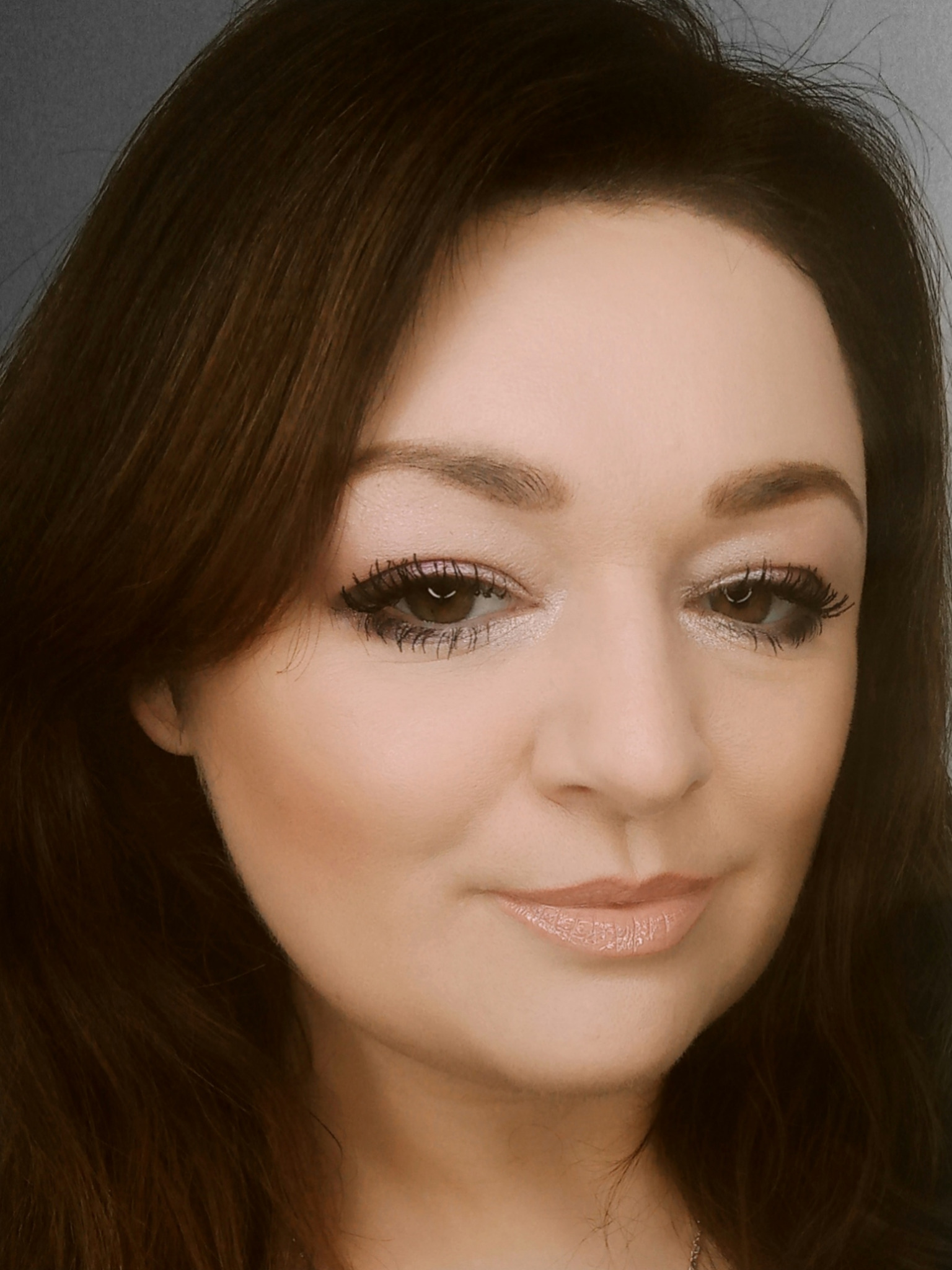 Portret kobiety z subtelnym makijażem: podkreślone oczy z długimi rzęsami i delikatnie zaznaczone usta w odcieniach nude. Widoczny profil twarzy, brązowe włosy.