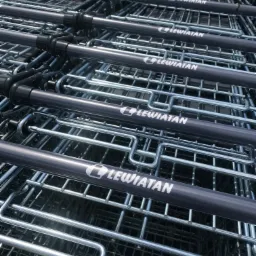 Stos metalowych wózków sklepowych z szarymi uchwytami i białym logo 'Lewiatan' na każdym uchwycie, ułożonych jeden w drugim.