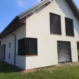 Nowoczesny dom z żaluzjami fasadowymi Z90 w kolorze antracyt, widoczne z zewnątrz, w słoneczny dzień.