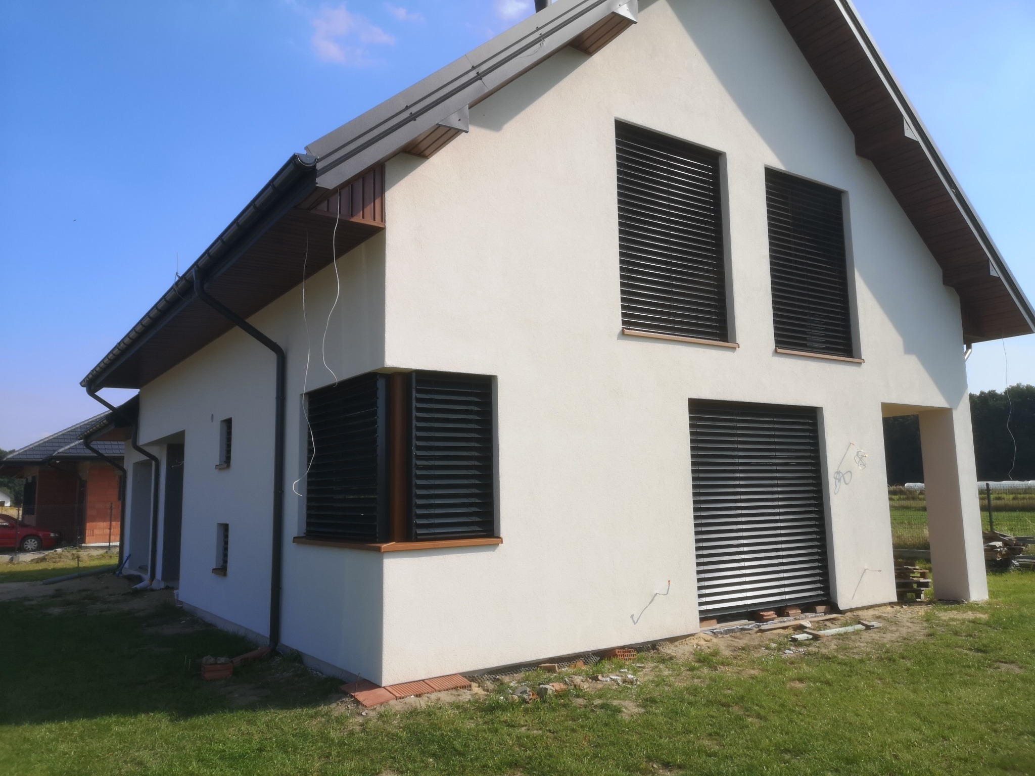 Nowoczesny dom z żaluzjami fasadowymi Z90 w kolorze antracyt, widoczne z zewnątrz, w słoneczny dzień.