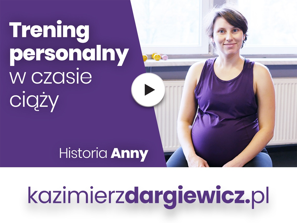 Kobieta w ciąży w fioletowej koszulce bez rękawów, siedząca na podłodze przed oknem, uśmiechnięta, z widocznym brzuchem ciążowym.