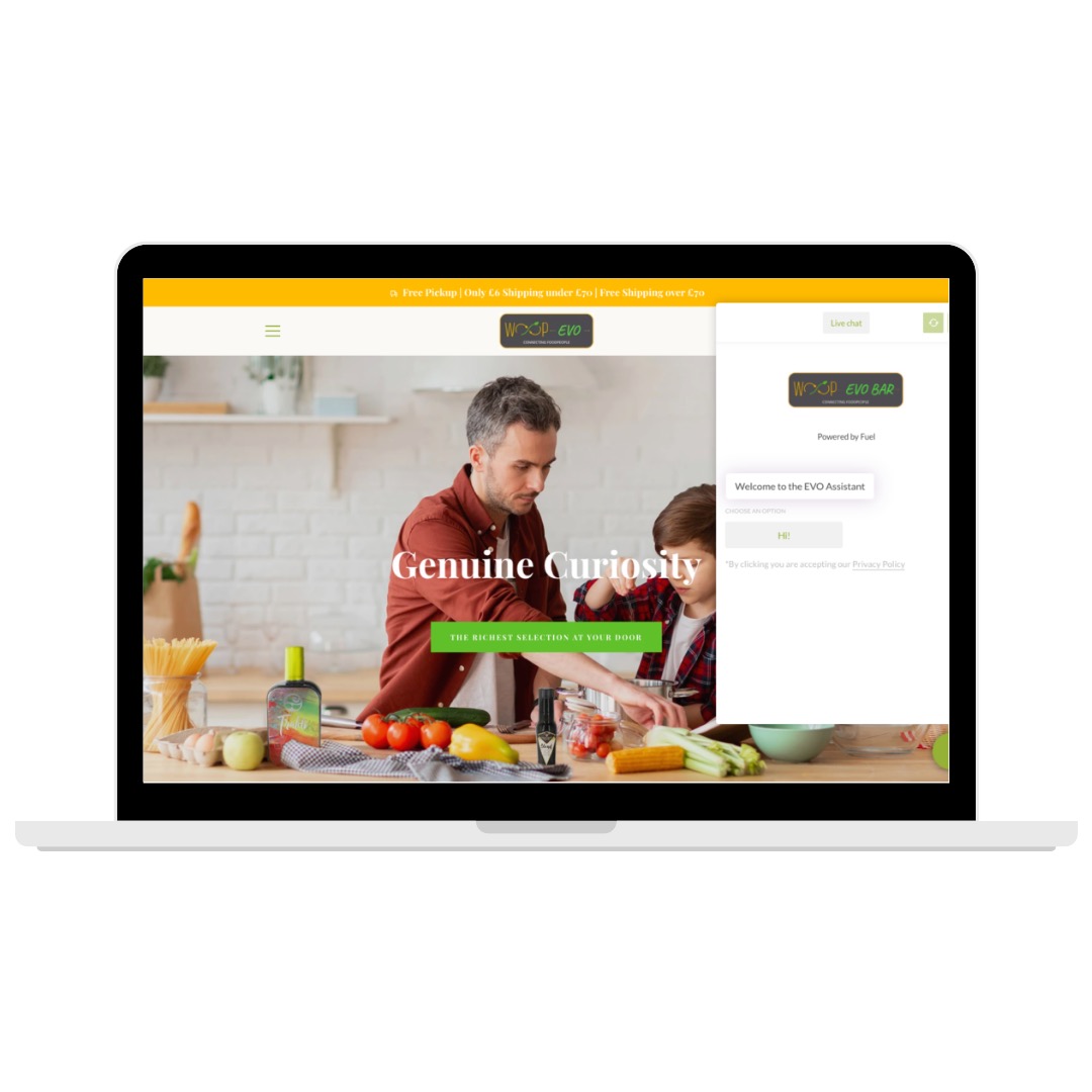 Laptop wyświetla stronę internetową z nagłówkiem 'Genuine Curiosity' i zdjęciem ojca z synem przygotowujących posiłek, obok widoczny otwarty czat z logo 'WOOP EVO BAR'.