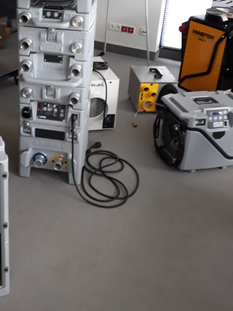 Profesjonalny sprzęt do osuszania budynków marki Aerial ustawiony na podłodze w Krakowie, widoczne kable i różne modele urządzeń.