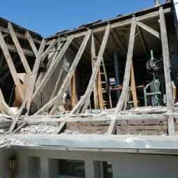 Usługi Dekarskie - Demontaż starego dachu z widoczną konstrukcją drewnianą, ceglanym kominem i fragmentem zamontowanej rynny.