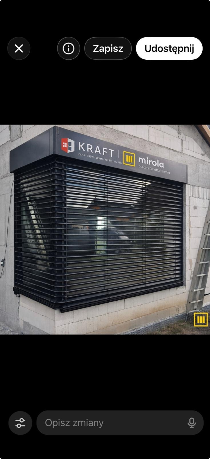 Zamknięta, czarna roleta zewnętrzna na oknie budynku w trakcie budowy. Nad roletą widoczny szyld firmy KRAFT/mirola.