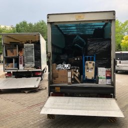 Edelweys Sp. z o.o. Andrii Doroshenko - Dwa samochody dostawcze z otwartymi rampami załadowane meblami i sprzętami, przygotowane do transportu podczas przeprowadzki.