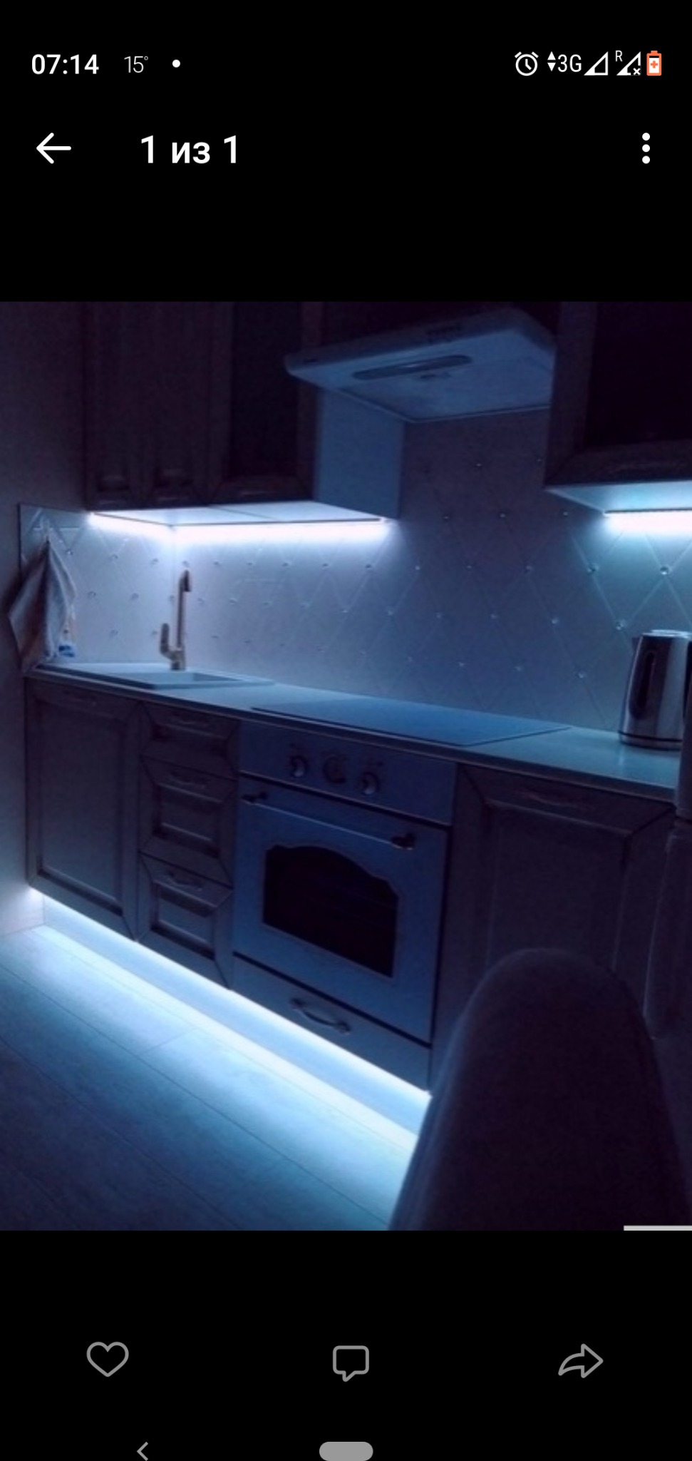 Kuchnia z białymi szafkami, oświetleniem LED podszafkowym i podłogowym, widoczna bateria, płyta indukcyjna i czajnik elektryczny, ujęcie z dołu w słabym oświetleniu.