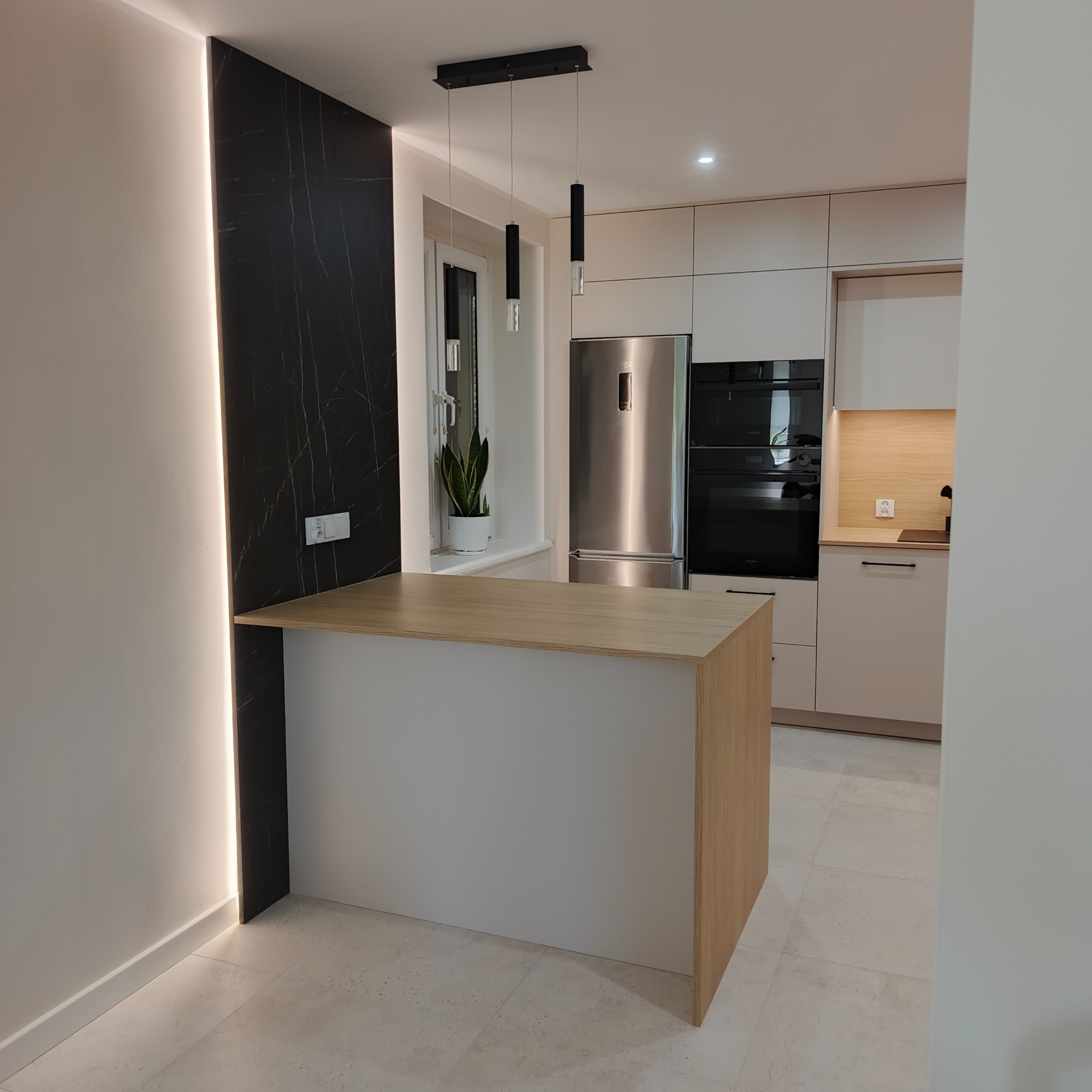 Nowoczesna kuchnia z wyspą i czarnym marmurem podświetlonym LED,  minimalistyczne lampy wiszące, zabudowa w jasnych kolorach. Eleganckie wykończenie.