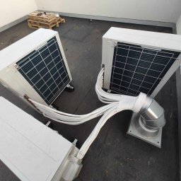 Nosek- Serwis Chłodniczy - Trzy zewnętrzne jednostki klimatyzacyjne na płaskim dachu, połączone rurami, widoczne palety w tle.