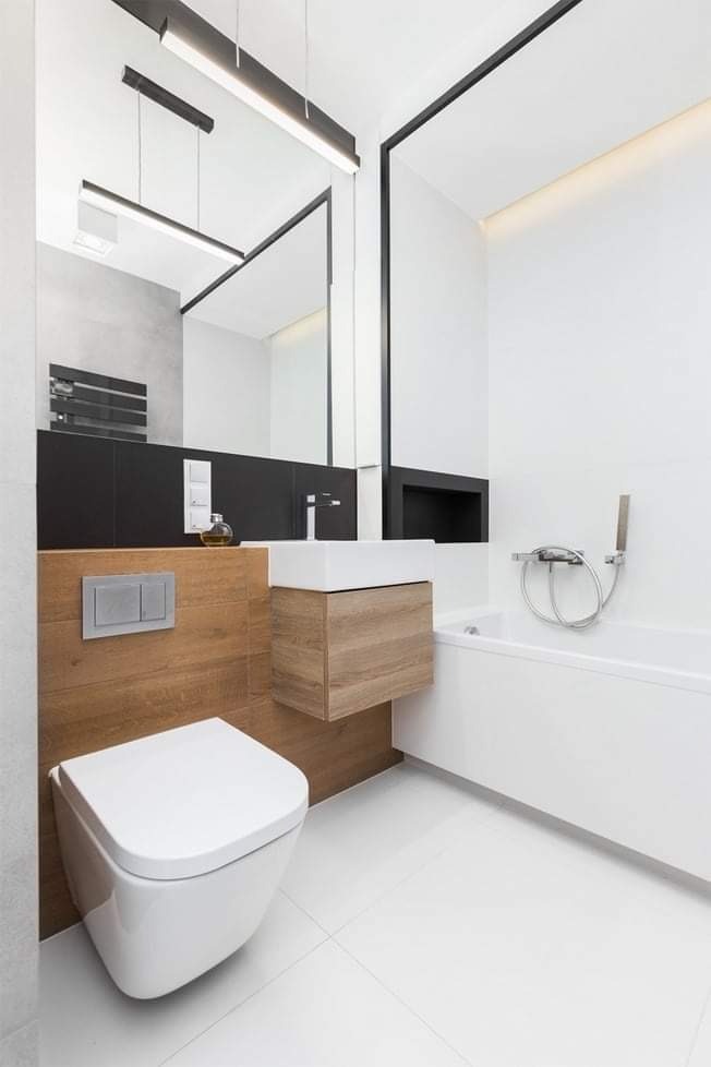 Nowoczesna łazienka w bieli z drewnianymi akcentami, podwieszana toaleta, umywalka z szafką i minimalistyczna armatura.