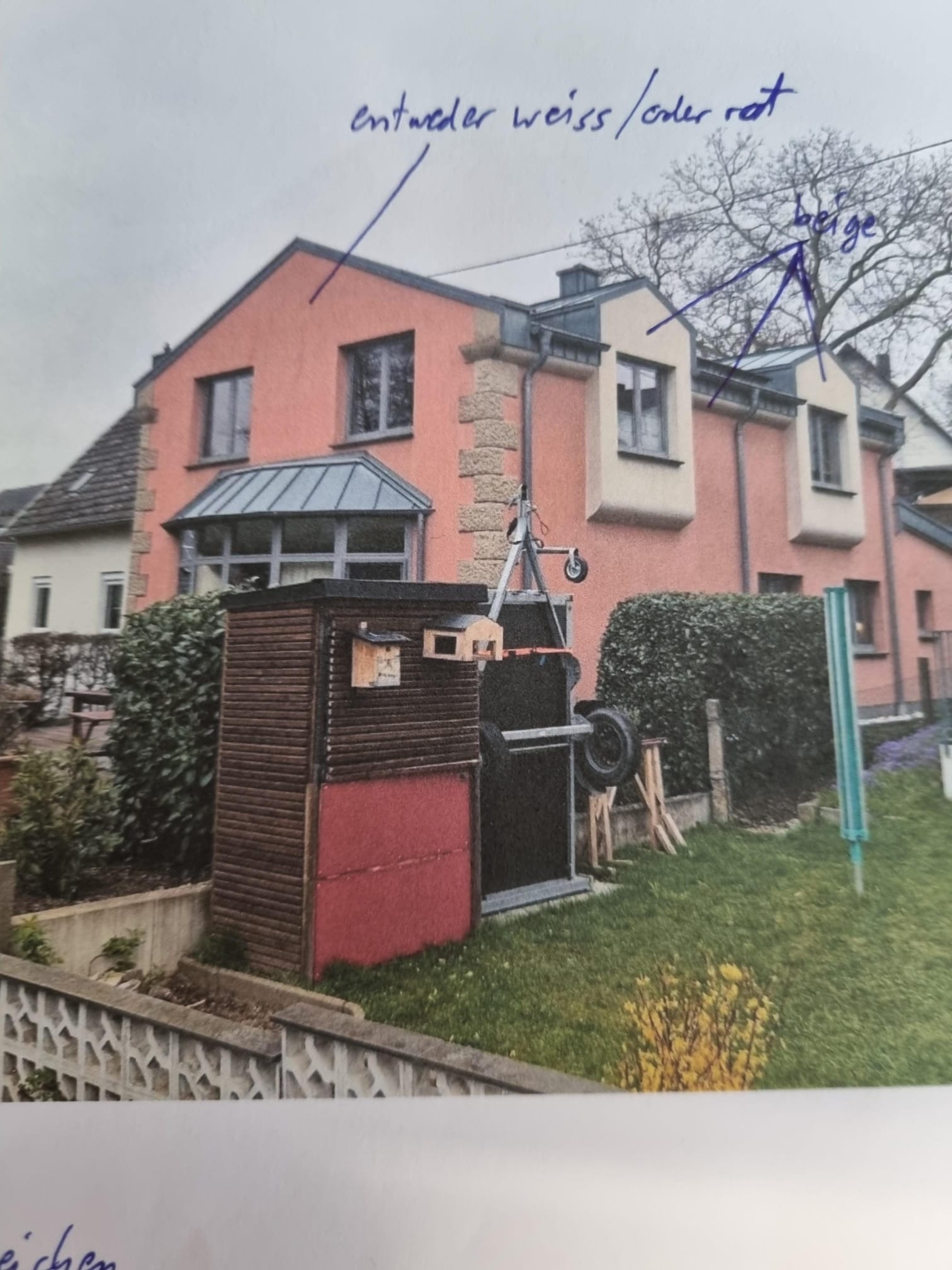 Dwupiętrowy dom z różową elewacją, beżowymi akcentami i szarą stolarką okienną, widoczny z perspektywy ogrodu z drewnianą szopą i sprzętem budowlanym.