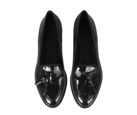 Para czarnych, lakierowanych mokasynów z frędzlami, widok z góry na białym tle.