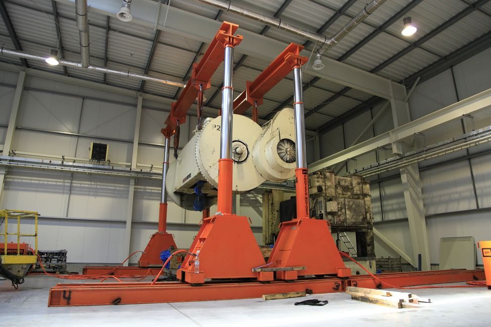 Montaż turbiny przemysłowej za pomocą specjalistycznego dźwigu w hali produkcyjnej.