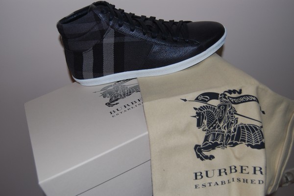 Czarno-szare buty sportowe Burberry na tle pudełka i worka z logo firmy, prezentacja produktu w neutralnym oświetleniu.