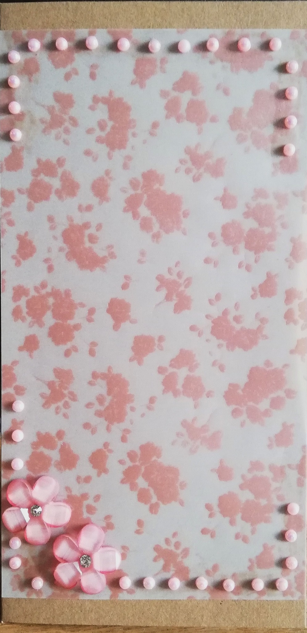 Ręcznie robiona kartka imieninowa w stylu scrapbookingu, z różowym kwiatowym tłem, obramowaniem z różowych koralików i dwoma różowymi kwiatkami z błyszczącymi kryształkami.