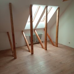 Zakład usługowy Piotr Pionk - Konstrukcja drewniana poddasza z oknami dachowymi, widoczne elementy nośne i krokwie przed ociepleniem, podłoga wyłożona panelami.