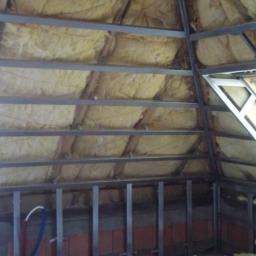 Zakład usługowy Piotr Pionk - Konstrukcja metalowa pod płyty gipsowo-kartonowe na poddaszu z oknem dachowym, ocieplona wełną mineralną, widoczne fragmenty instalacji wodnej i muru z cegły.