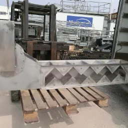 Element konstrukcji ze stali nierdzewnej z wyciętymi trójkątnymi otworami, umieszczony na palecie i transportowany wózkiem widłowym do wnętrza ciężarówki.