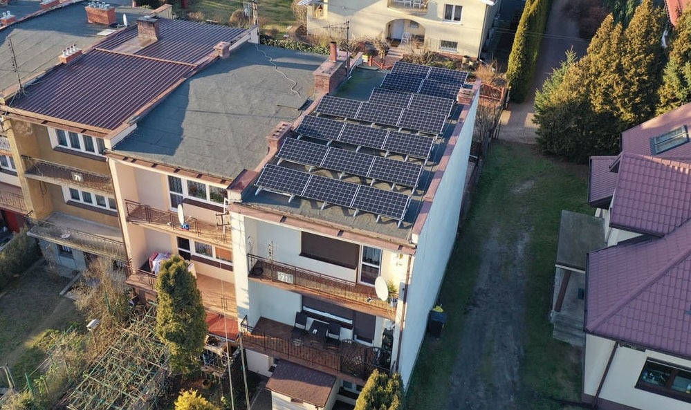 Instalacja fotowoltaiczna na płaskim dachu trzypiętrowego budynku mieszkalnego z balkonami, widok z góry, panele LONGI, inwerter SOLAR EDGE, Wołomin.