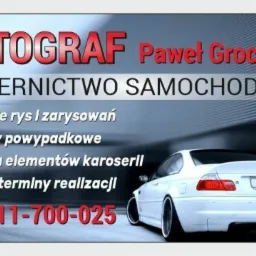 Reklama warsztatu samochodowego Autograf Pawła Grocheckiego, oferującego usuwanie rys, naprawy powypadkowe i wymianę elementów karoserii; w tle biały samochód BMW.