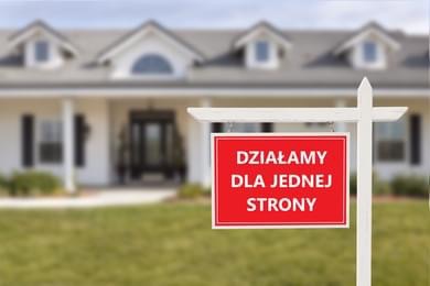 Czerwona tabliczka z napisem 'DZIAŁAMY DLA JEDNEJ STRONY' na tle białego domu jednorodzinnego z trzema oknami dachowymi.