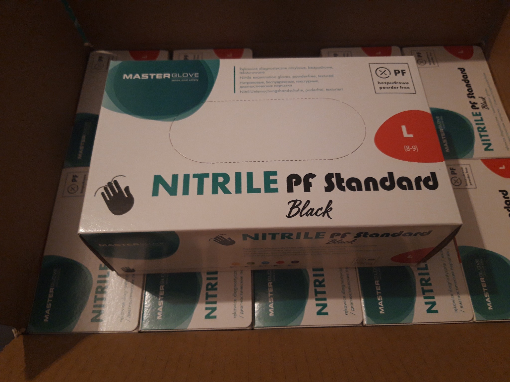 Kartonowe pudełka z nitrylowymi rękawicami diagnostycznymi w rozmiarze L, bezpudrowe, marki Master Glove, ułożone w kartonie zbiorczym.