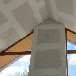 Sufit i ściana w trakcie prac przygotowawczych, widoczne nakładane warstwy materiału wykończeniowego, okna z drewnianymi ramami w tle, fragment osoby w dolnej części kadru.